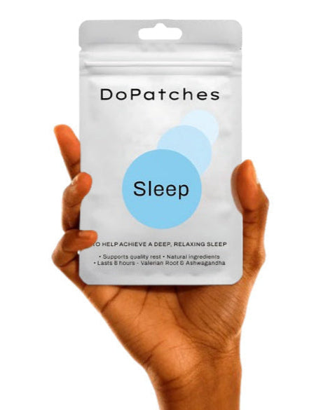 Hand holding a package of DoPatches Sleep patches on a white background